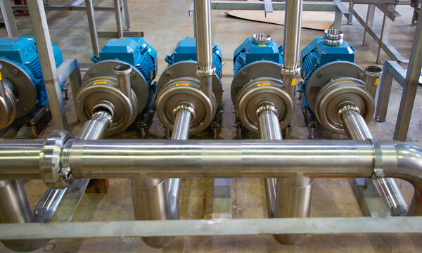 Stainless steel pumps and pipes installed to create pressure in the food and beverage industry systems.