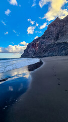 Scenic view during sunset on the volcanic sand beach Playa del Ingles in Valle Gran Rey, La Gomera, Canary Islands, Spain, Europe. Footprints leading to the massive cliffs of the La Mercia mountains