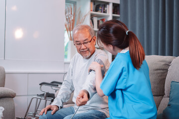Asian caregiver doctor examine older patient use blood pressure gauge. nurse visit and taking care patient senior man checkup elderly old man in living room, Healthcare insurance concept.