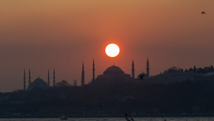 The view of the Blue Mosque and Hagia Sophia at sunset and after sunset was photographed with a...