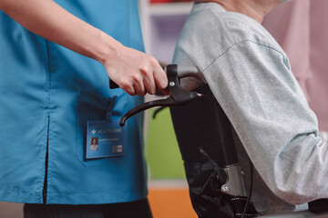 Close up of caregiver nurse support senior elderly man on wheelchair in living room. nurse female take care of mature patient doing physical therapy at nursing home. Health care concept.