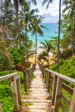 Wood stairs steps down to Naithon Beach turquoise water Thailand.