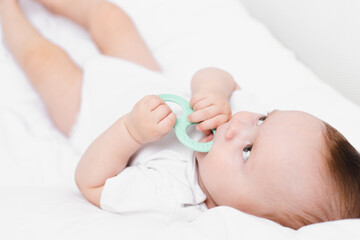 Fototapeta na wymiar A baby with a teether on a white background . Teething. Children's article.