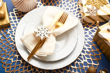 Christmas festive table setting with white plates and gold cutlery, gifts in white and gold paper, decorations and balls.