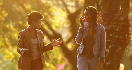 Two women in conversation outside in street with sunlight
