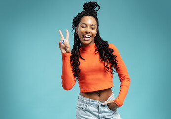 Young smiling friendly positive fun cheerful woman 20s showing victory sign isolated on blue backround studio portrait - obrazy, fototapety, plakaty