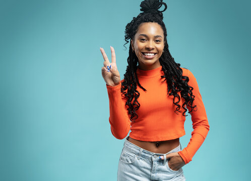 Young smiling friendly positive fun cheerful woman 20s showing victory sign isolated on blue backround studio portrait