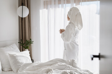 Woman with coffee cup in hands in hotel room