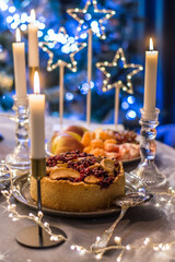 Christmas table with candles and lights with homemade cranberry and apple pie