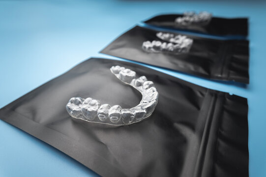new transparent plastic braces lie on a special orthodontic package with a zipper on a blue background, studio shot, nobody