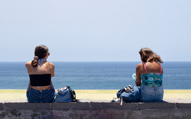 girls on a low wall with the sea in the background in Ischia