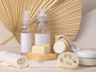 Fototapeta na wymiar Cosmetic bottles and soap bars on stone against dry beige palm leaf close up, label mockup