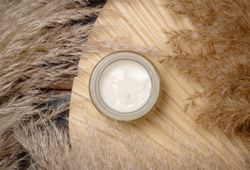 Opened cream jar on dried palm leaf near pampas grass. Cosmetic Mockup
