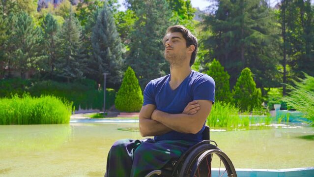 Young man in wheelchair outdoors.
Young disabled man sitting in wheelchair in nature park.
