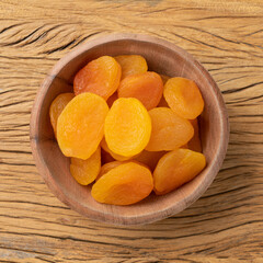 Dried apricots in a bowl over wooden table