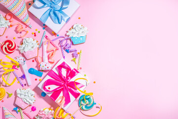 Happy birthday greeting card background. Flatlay with colorful holiday tools - birthday party caps, blowers, gift boxes , balloons, steamers, candles, on pink background copy space