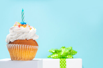Birthday greeting card simple background. Homemade cupcake with candle for birthday holiday celebration, with gift box on background copy space