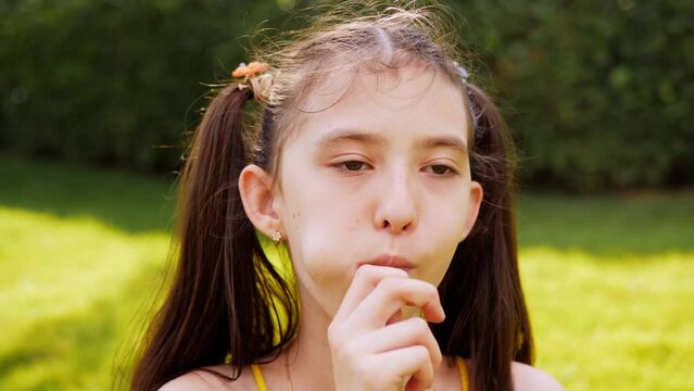Close-up of an 8-year-old girl eating a lollipop in close-up.