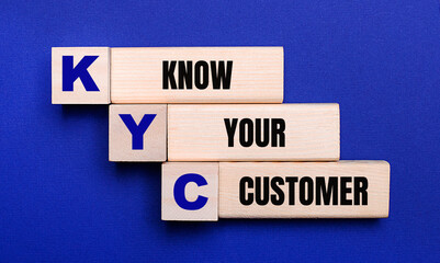 On a bright blue background, light wooden blocks and cubes with the text KYC KNOW YOUR CUSTOMER