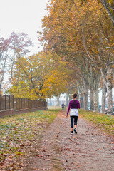 Fototapeta premium Sport in the autumn park. Woman running jogging on a autumn park path. Mock up and copy space.