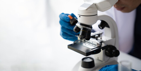 Doctor hand taking a blood sample tube from a rack with machines of analysis in the lab background, Technician holding blood tube test in the research laboratory.