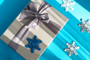 Gray gift box with bow and big snowflakes on blue background