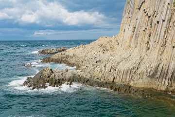 rocky seashore formed by columnar basalt against the backdrop of a sea, coastal landscape of the Kuril Islands