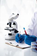 Doctor hand taking a blood sample tube from a rack with machines of analysis in the lab background,...