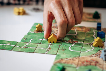 A group of young people play board games at home in the kitchen.Hands close-up.Time together.Stay home,board games concept.Selective focus.