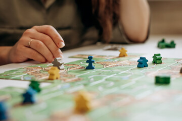 Women’s hands holding game pieces over the game field.Board games concept.Selective focus,close up.