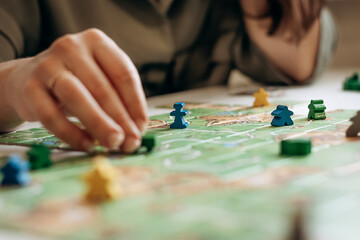 Women’s hands holding game pieces over the game field.Board games concept.Selective focus,close up.
