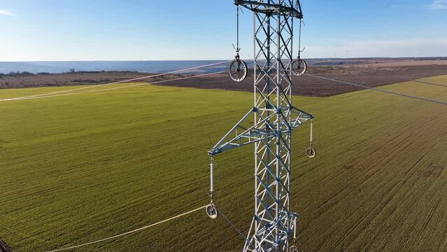 Aerial circling view of steel erector workers strengthen a newly installed power line pylon. Transmission tower or power tower
supporting an overhead high voltage power line. The pylon carries wires
