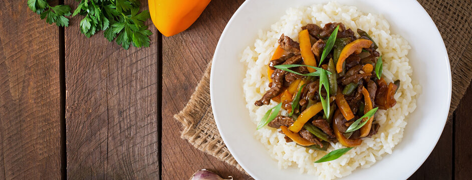 Stir frying beef with sweet peppers, green beans and rice