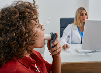 Male child during breathing spirometry and pulmonary function test using medical spirometer with...