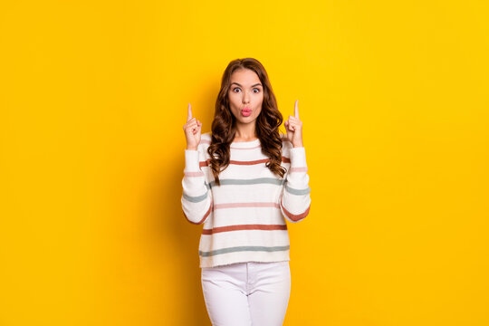 Photo of pretty impressed girl pouted lips direct fingers up empty space isolated on yellow color background
