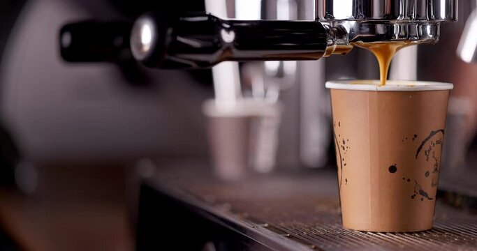 Coffee machine filling a cup with hot black espresso with foam. Barista make coffee with professional coffee machine. 