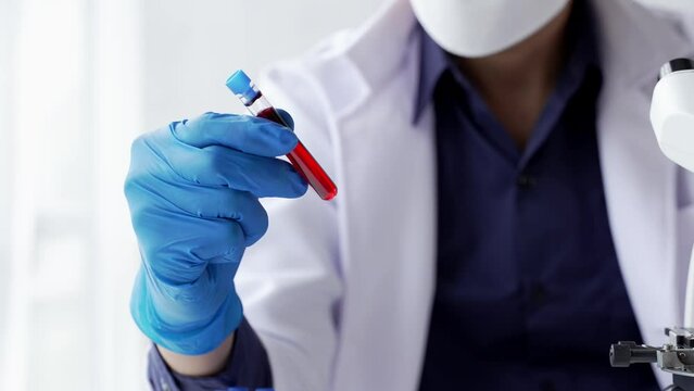 Doctor hand taking a blood sample tube from a rack with machines of analysis in the lab background, Technician holding blood tube test in the research laboratory.