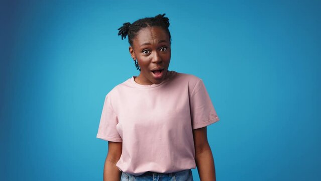 Shocked surprised young african woman against blue background
