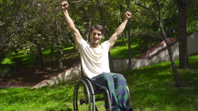Ambitious disabled young man.
Young disabled person in wheelchair rejoices and looks at camera.
