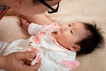  Handsome Asian father wearing pink shirt, Lying and teasing with his baby daughter, on a soft...