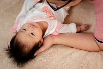 Close-up of Asian baby girl face, lying on a soft brown bed, And the father cherishes the little...
