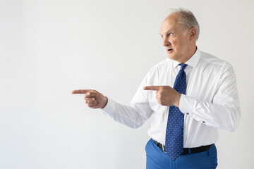 Portrait of confident mature businessman showing something. Senior man wearing formalwear looking away and pointing with finger at something. Advertising and presentation concept