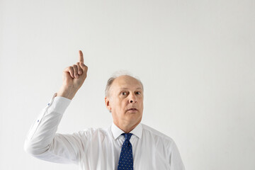 Portrait of confident mature businessman pointing upwards against white background. Senior manager wearing formalwear having idea. Solution and idea concept