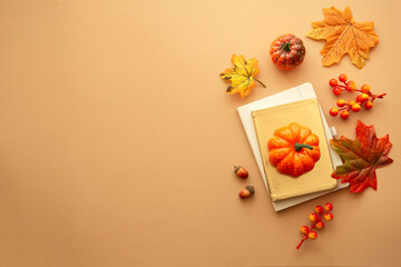 Autumn composition with fall leaves, pumpkins and notebook at orange background. Flat lay.
