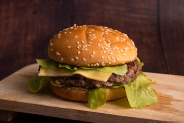 homemade hamburgers of beef, cheese and vegetables on an old wooden table. Fat unhealthy food close-up.