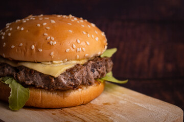 homemade hamburgers of beef, cheese and vegetables on an old wooden table. Fat unhealthy food close-up.