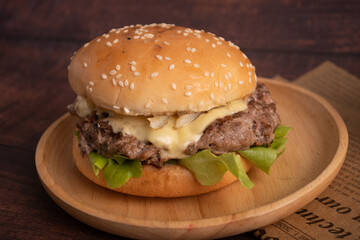 homemade hamburgers of beef, cheese and vegetables on an old wooden table. Fat unhealthy food close-up.