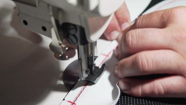 Close up of an Upholsterer sewing leather parts by machine, to repair a seat