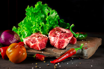 Raw juicy pork steaks and fresh vegetables before cooking