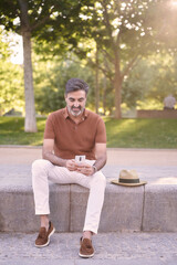 Obraz premium Man relaxing while using a mobile phone outdoors in a park. Technology concept.